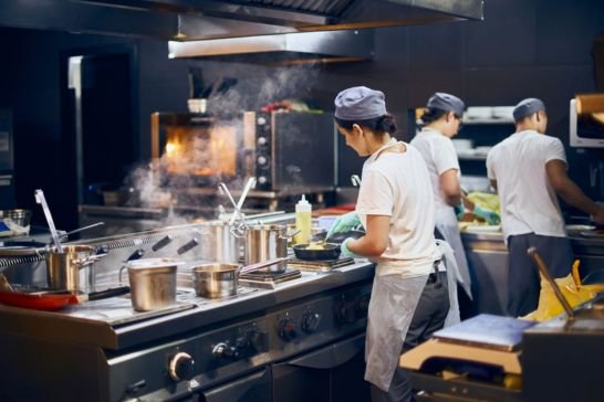 Equipo de cocina profesional utilizando hornos y cocinas industriales en restaurante, representando el servicio técnico especializado de Wiltec Service en Buenos Aires